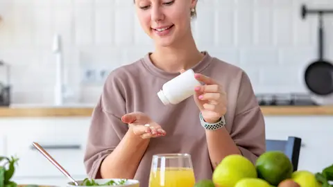 Una mujer toma medicinas con zumo Una mujer toma medicinas con zumo