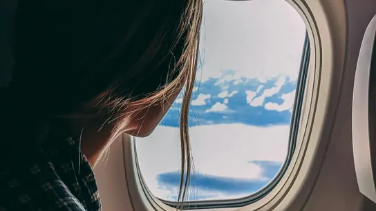 Mujer mirando por la ventanilla de un avión Mujer mirando por la ventanilla de un avión