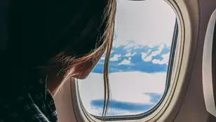 Mujer mirando por la ventanilla de un avión 