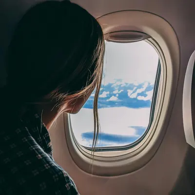 Mujer mirando por la ventanilla de un avión 