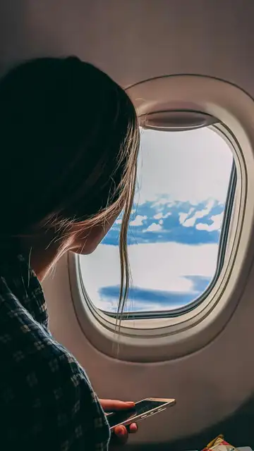 Mujer mirando por la ventanilla de un avión Mujer mirando por la ventanilla de un avión