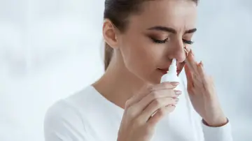 Una mujer usando un espray nasal descongestivo