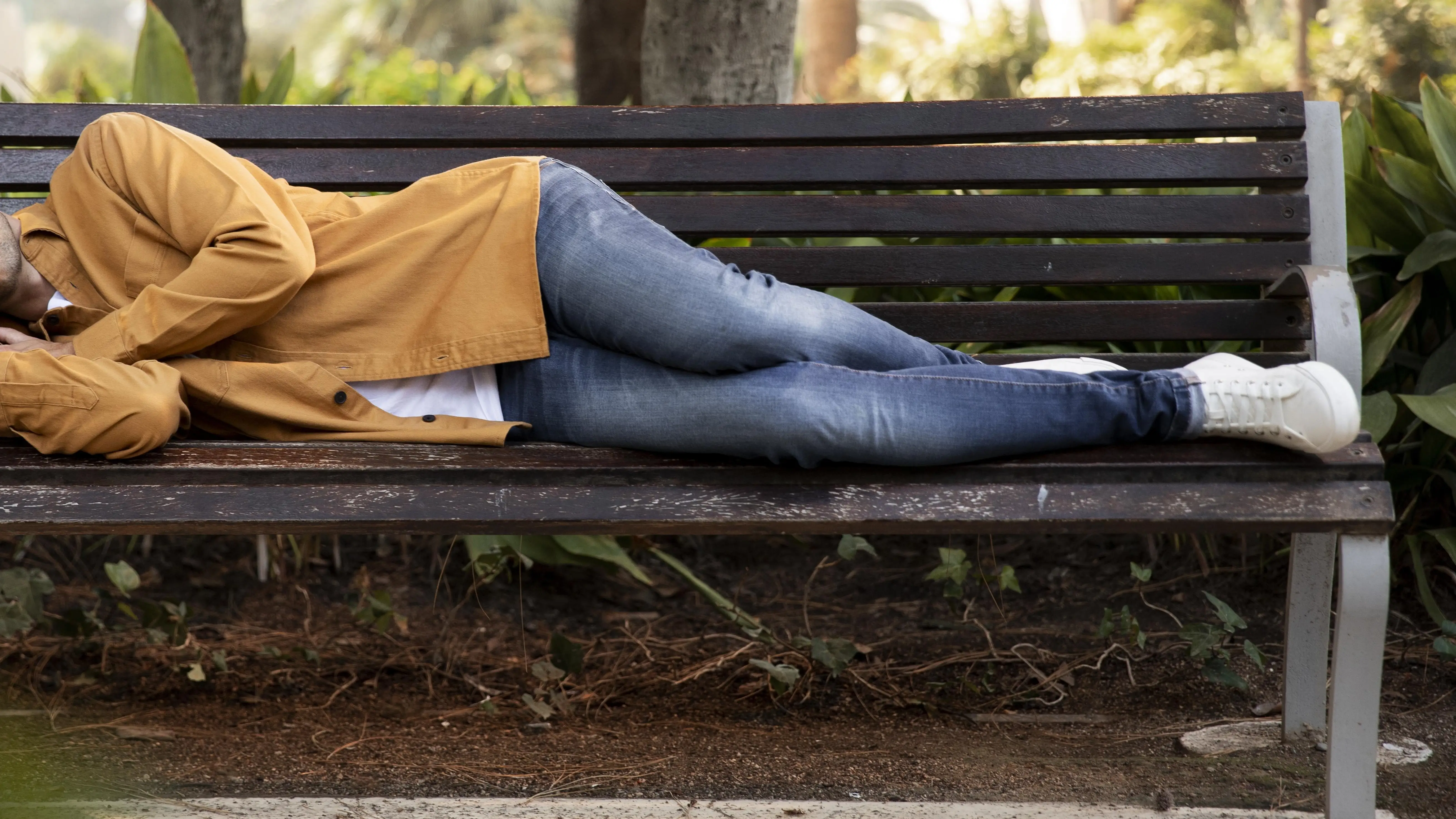 Un hombre durmiendo en un banco Un hombre durmiendo en un banco