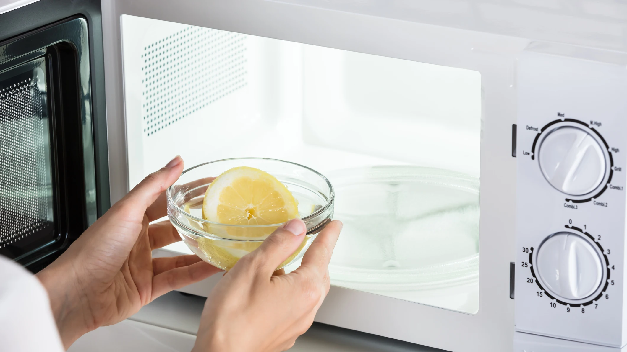 Persona metiendo un lim&oacute;n al microondas