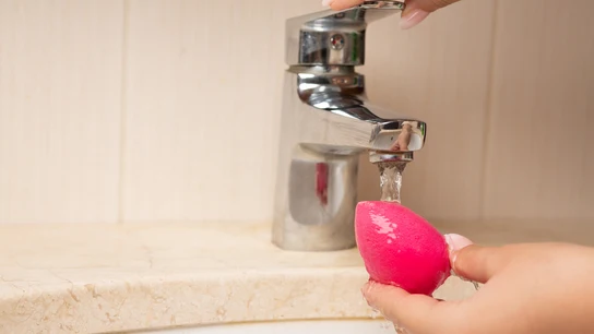 Mujer lavando una esponja de maquillaje Mujer lavando una esponja de maquillaje