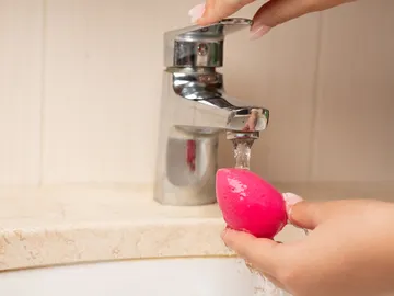 Mujer lavando una esponja de maquillaje Mujer lavando una esponja de maquillaje