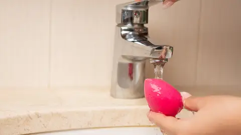 Mujer lavando una esponja de maquillaje Mujer lavando una esponja de maquillaje