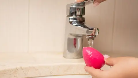Mujer lavando una esponja de maquillaje Mujer lavando una esponja de maquillaje