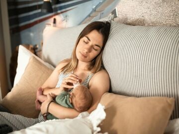 Una mujer dando en biberón a su bebé durante el posparto