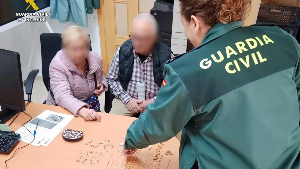 Agentes de la Guardia Civil les devuelven las joyas recuperadas.