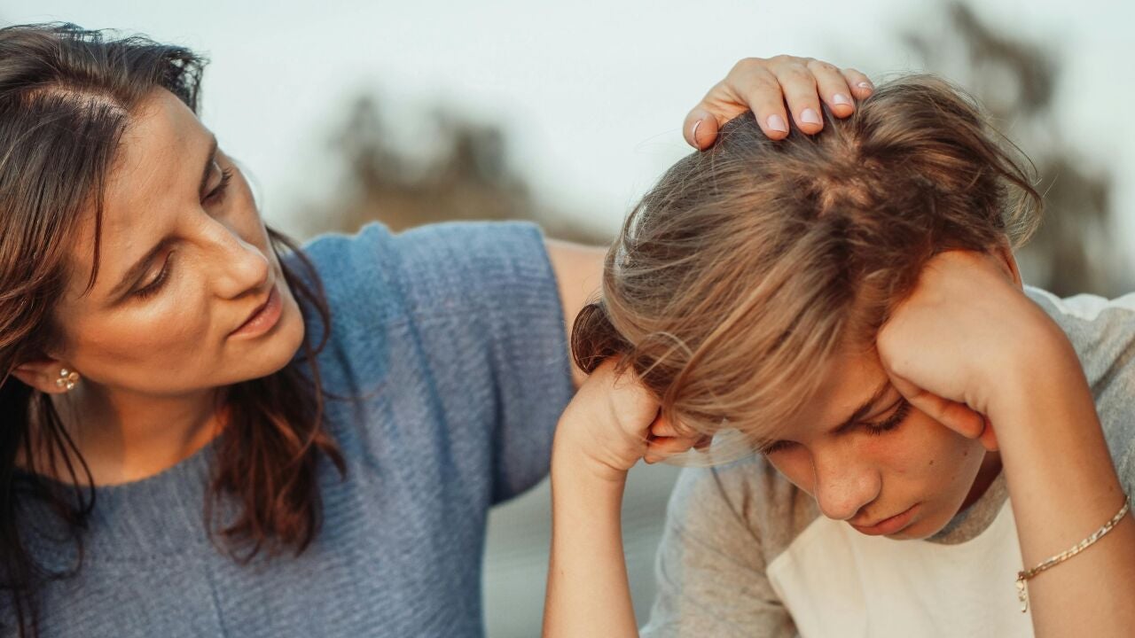 adolescente sentado solo, mirando su celular, espalda a la cámara