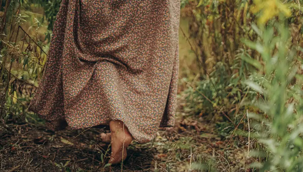 Una mujer caminando descalza en el bosque.