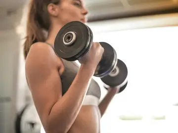 Una mujer entrena fuerza con pesas. Una mujer entrena fuerza con pesas.
