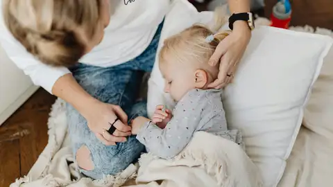 Una niña enferma descansando junto a su madre Una niña enferma descansando junto a su madre
