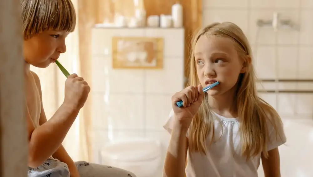 Una niña y un niño lavándose los dientes