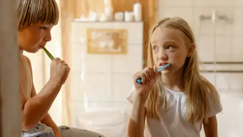 Una niña y un niño lavándose los dientes Una niña y un niño lavándose los dientes