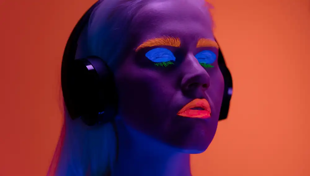 Mujer maquillada con colores flúor escuchando música