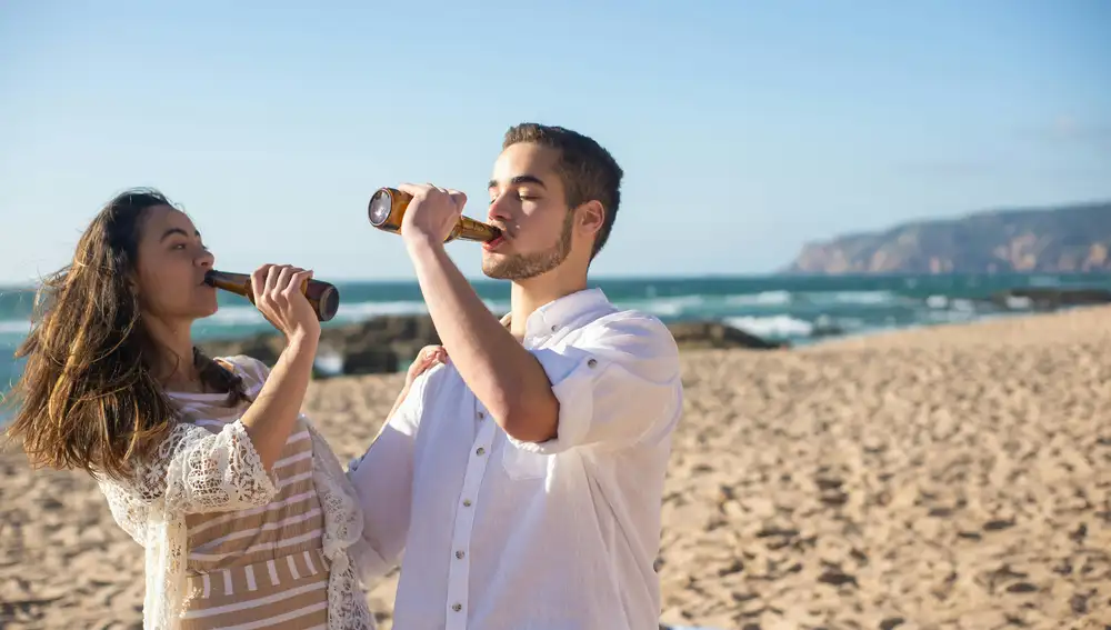Jóvenes beben alcohol en la playa.