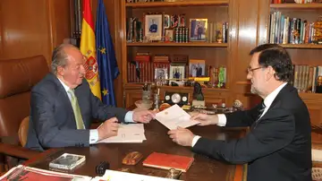 Don Juan Carlos firma el documento de su abdicación que entrega al presidente del Gobierno, Mariano Rajoy