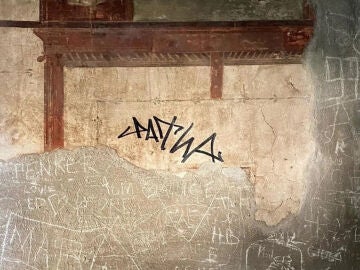 Un turista firma con permanente un fresco de Herculano, Italia