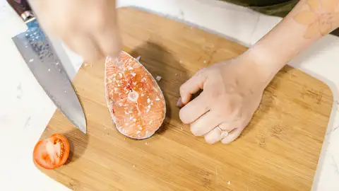 Una mujer sala el salmón antes del cocinado Una mujer sala el salmón antes del cocinado