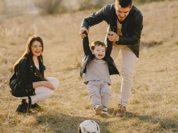 Una madre y un padre juegan a la pelota con su hijo 