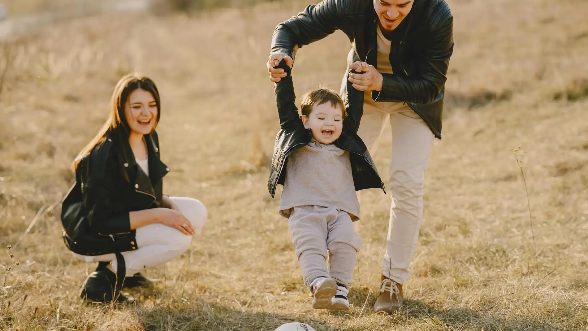Una madre y un padre juegan a la pelota con su hijo Una madre y un padre juegan a la pelota con su hijo