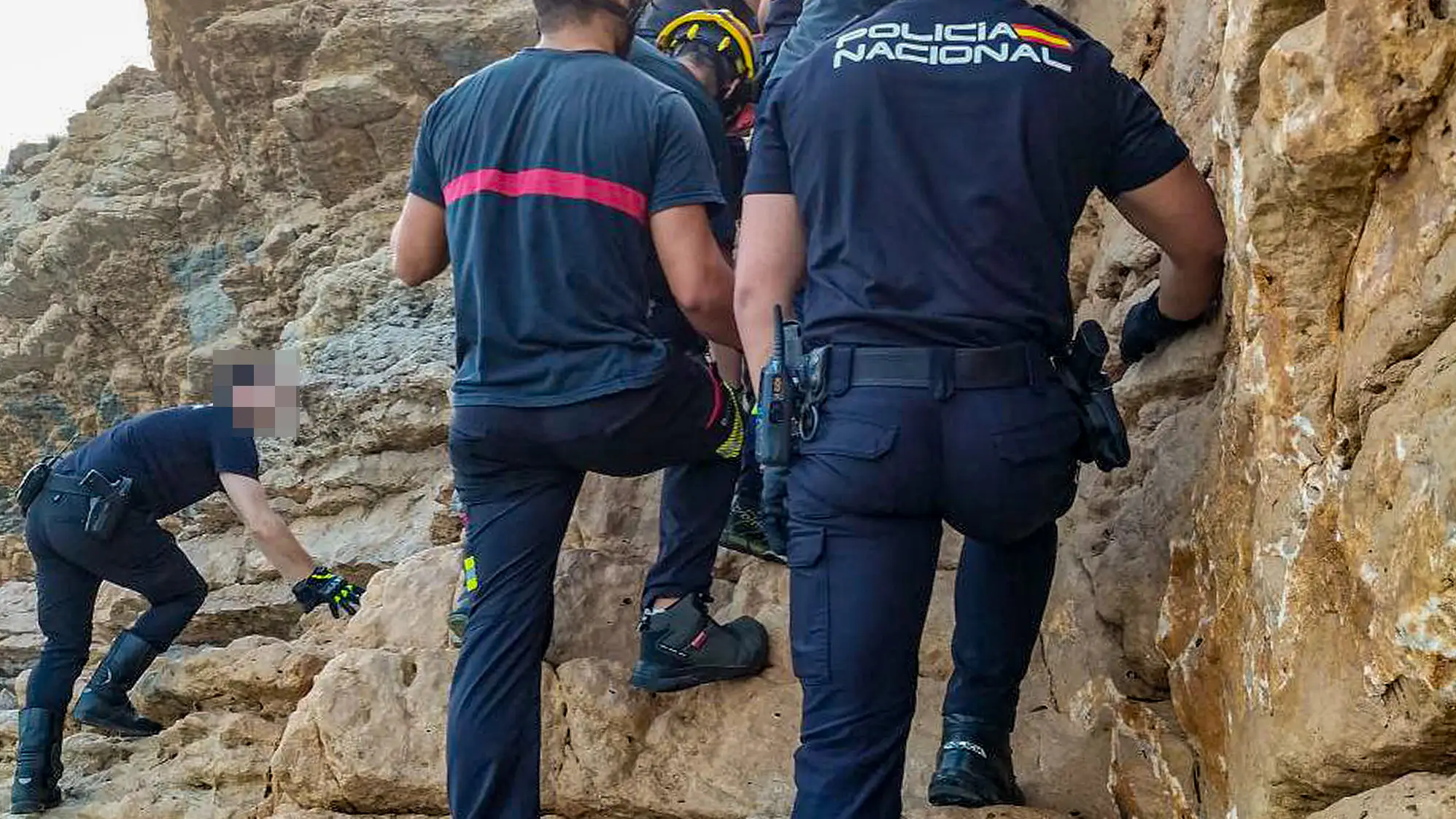 Los bomberos socorren al joven en una zona rocosa