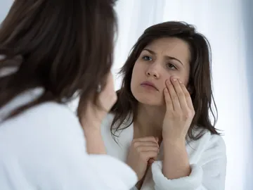 Mujer observando sus ojeras Mujer observando sus ojeras