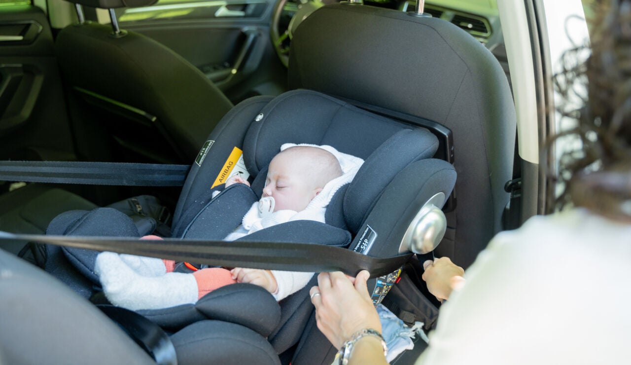 Una mujer ajusta una sillita infantil en el coche.