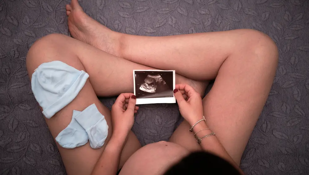Una mujer embarazada mira la imagen de una ecografía