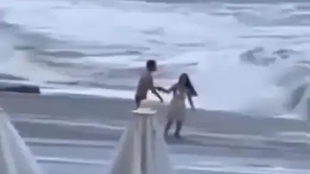 La pareja jugando entre las olas