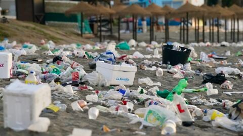 Botellas y envases de pl&aacute;stico inundan la arena de una playa 