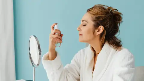 Chica se aplica producto en spray en el rostro Chica se aplica producto en spray en el rostro