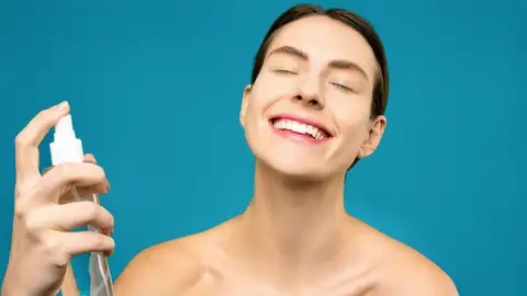 Chica se aplica producto en spray en el rostro Chica se aplica producto en spray en el rostro