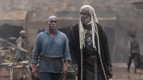 Abubakar Salim y Steve Toussaint como Alyn de Hull y Corlys Velaryon en La Casa del Dragón Abubakar Salim y Steve Toussaint como Alyn de Hull y Corlys Velaryon en La Casa del Dragón