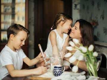 Madre sentada en la mesa con sus dos hijos