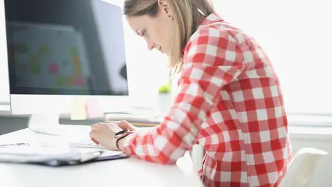 Una persona mal sentada trabajando Una persona mal sentada trabajando