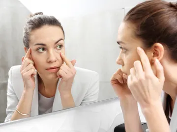 Mujer mirándose al espejo las ojeras Mujer mirándose al espejo las ojeras