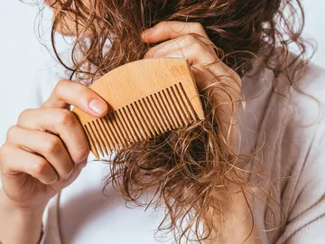 Mujer con pelo encrespado intentando peinarse Mujer con pelo encrespado intentando peinarse