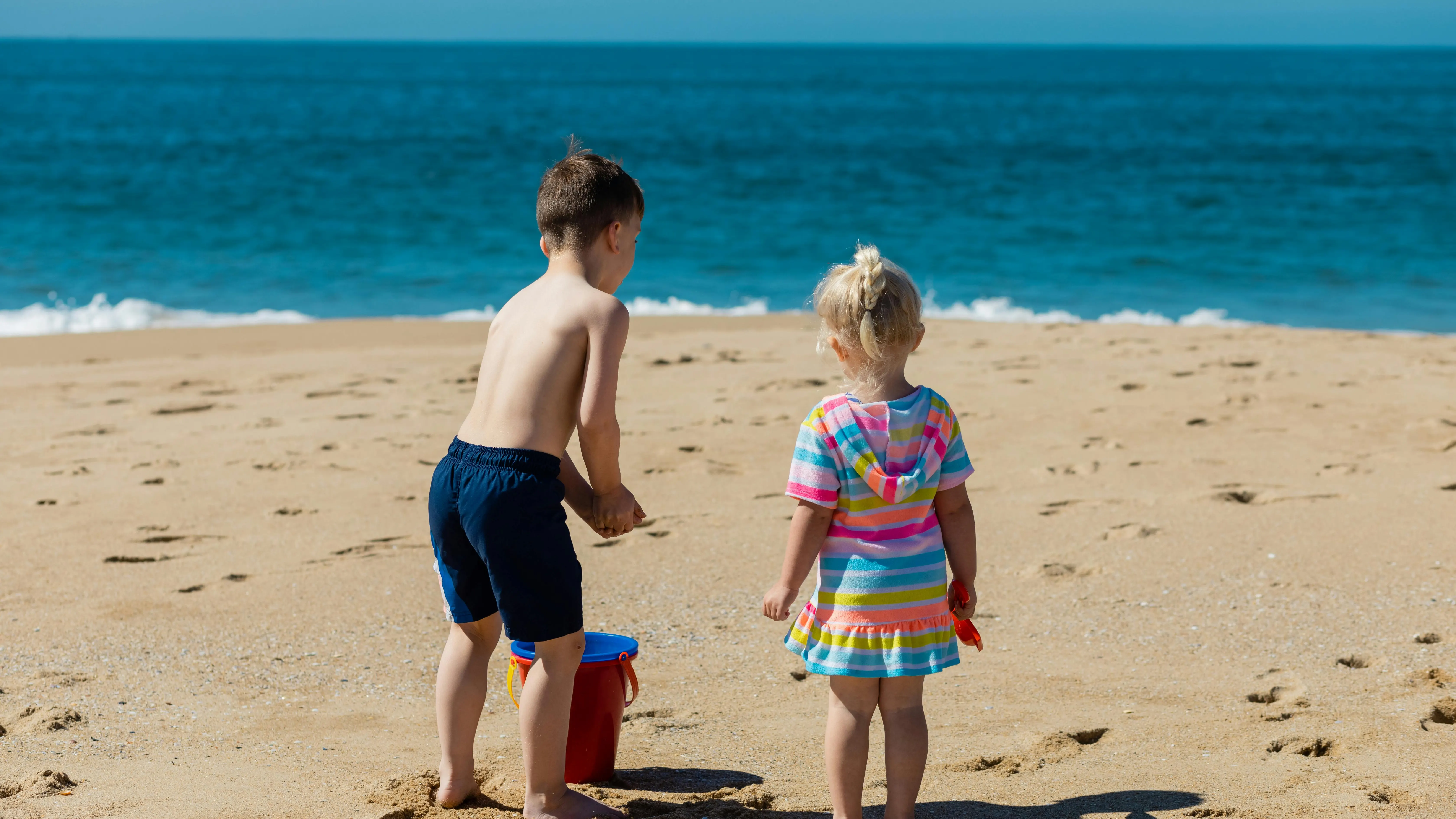 Un niño y una niña juegan en la arena de la playa Un niño y una niña juegan en la arena de la playa