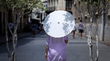 Una mujer se protege del sol con un paraguas