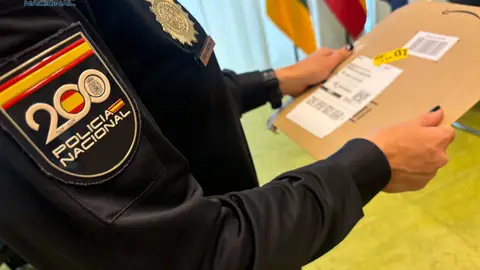 Un agente sostiene un paquete con información sensible Un agente sostiene un paquete con información sensible