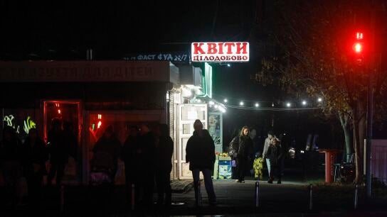 La gente camina en una zona residencial en la oscuridad durante un corte de energ&iacute;a programado en Kiev