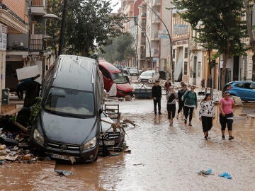 Calle cubierta de lodo y coches amontonados tras la DANA en Valencia.