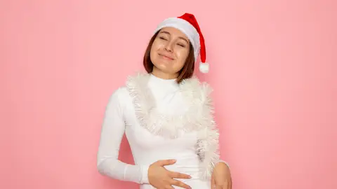 Mujer vestida de Navidad tocándose el abdomen Mujer vestida de Navidad tocándose el abdomen