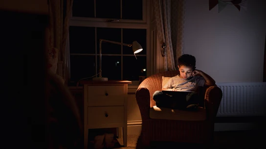 Un niño leyendo a oscuras con un flexo Un niño leyendo a oscuras con un flexo