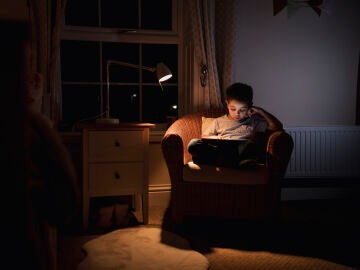 Un niño leyendo a oscuras con un flexo