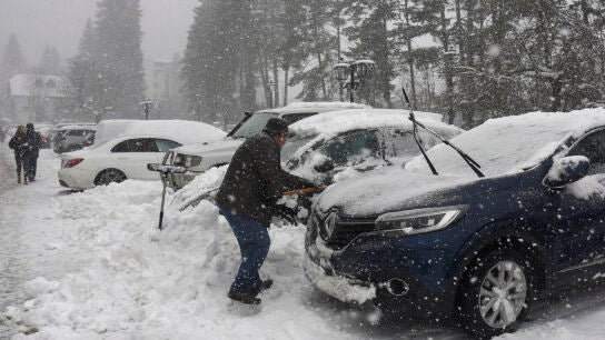 Turistas y habitantes de Canfranc quitan la nieve de sus coches con palas debido a la nieve ca&iacute;da.