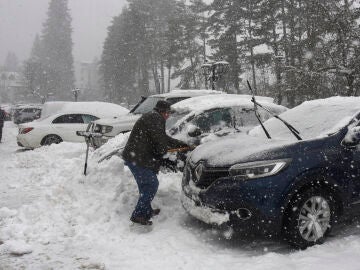 Turistas y habitantes de Canfranc quitan la nieve de sus coches con palas debido a la nieve caída.